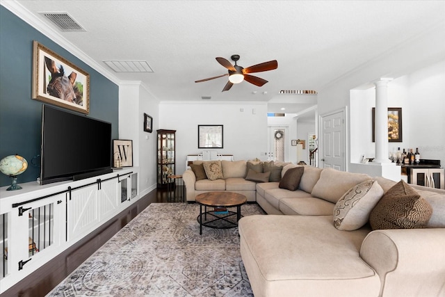 living area with visible vents, dark wood-style flooring, a ceiling fan, and ornamental molding