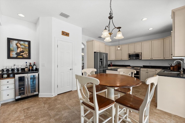 kitchen featuring visible vents, cream cabinetry, a sink, stainless steel appliances, and wine cooler