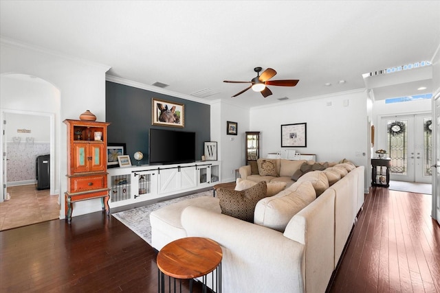 living area featuring ceiling fan, arched walkways, dark wood-style flooring, and ornamental molding