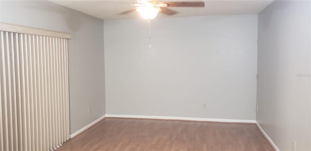 spare room featuring baseboards, wood finished floors, and a ceiling fan