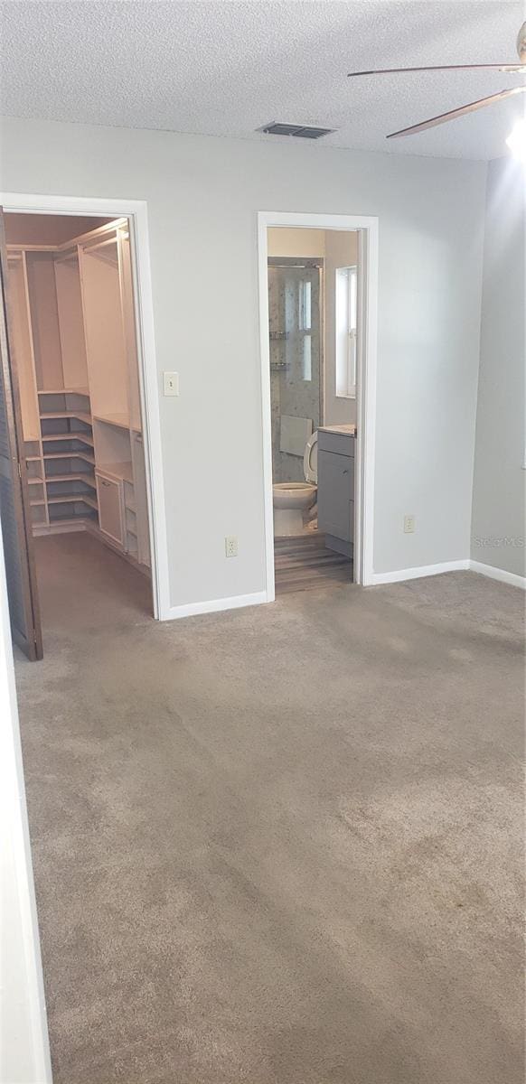 spare room featuring visible vents, carpet flooring, a textured ceiling, and baseboards