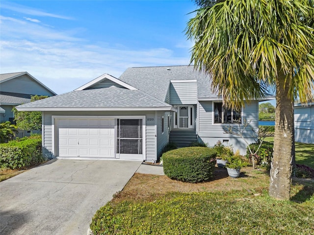 view of front of house with a garage, a front yard, roof with shingles, and driveway