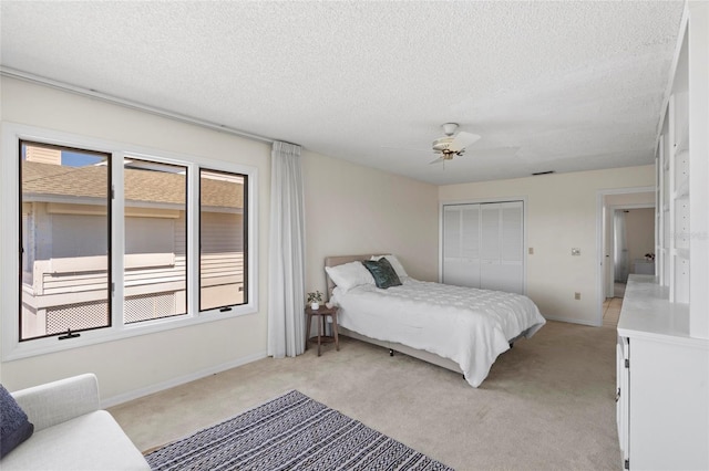 bedroom with ceiling fan, a textured ceiling, a closet, and light carpet