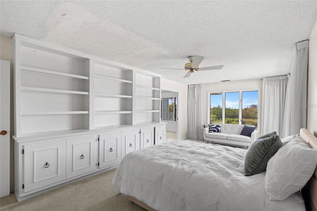 bedroom with ceiling fan, light colored carpet, and a textured ceiling