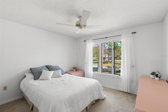 bedroom featuring light colored carpet, a textured ceiling, and baseboards