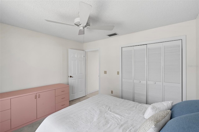 bedroom featuring a ceiling fan, visible vents, a closet, and a textured ceiling