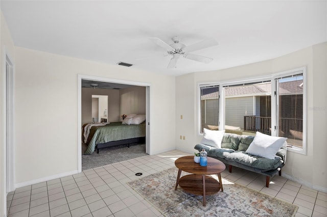 living room featuring light tile patterned floors, visible vents, baseboards, and a ceiling fan