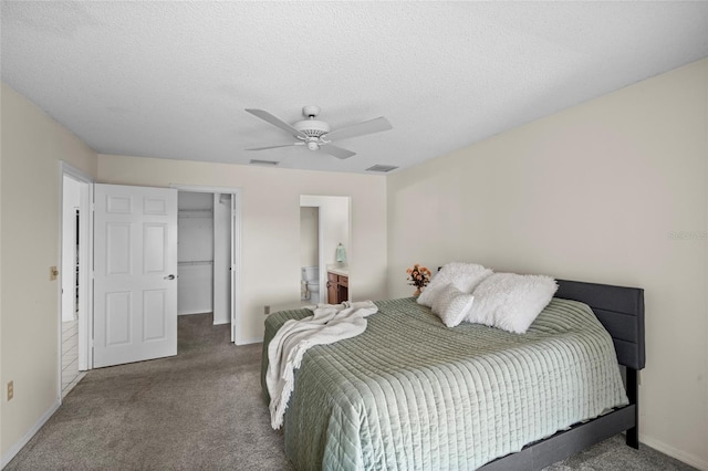 bedroom featuring visible vents, a walk in closet, a textured ceiling, carpet flooring, and ceiling fan