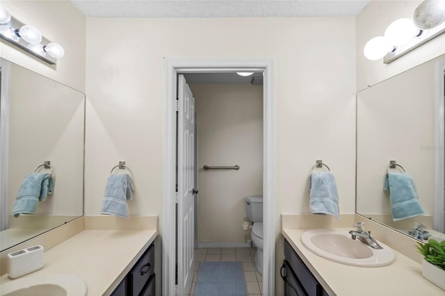 bathroom with tile patterned floors, a textured ceiling, toilet, and vanity