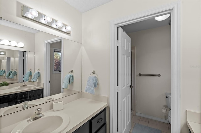 bathroom featuring tile patterned flooring, toilet, vanity, and baseboards