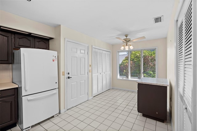 kitchen featuring visible vents, a ceiling fan, freestanding refrigerator, light countertops, and dark brown cabinets