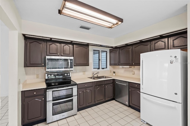 kitchen featuring dark brown cabinets, appliances with stainless steel finishes, light countertops, and a sink