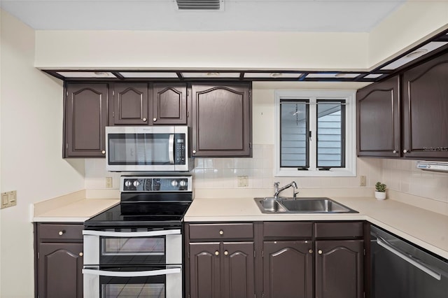 kitchen with a sink, stainless steel appliances, decorative backsplash, and light countertops