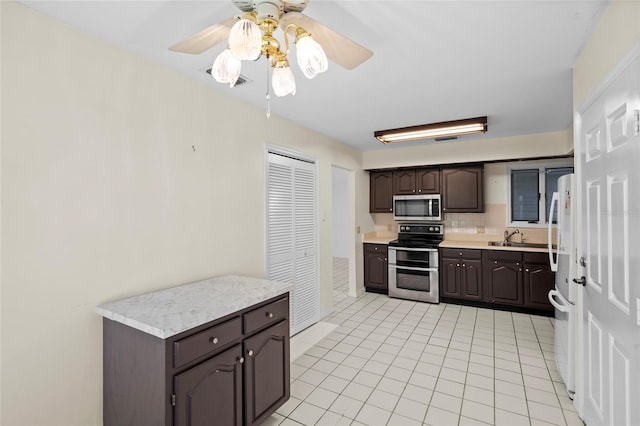 kitchen featuring a sink, decorative backsplash, light countertops, dark brown cabinets, and appliances with stainless steel finishes