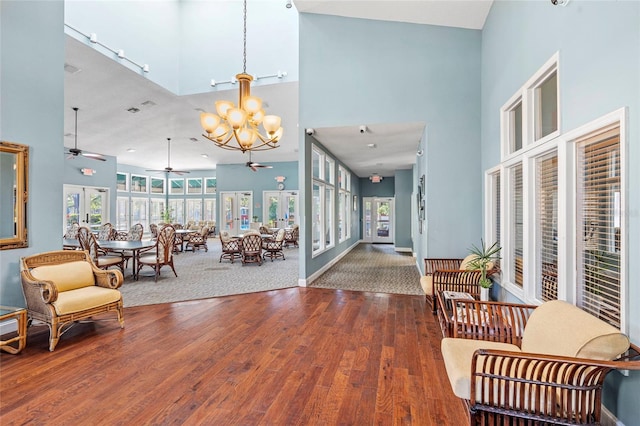 entrance foyer with wood finished floors, baseboards, a high ceiling, french doors, and ceiling fan with notable chandelier