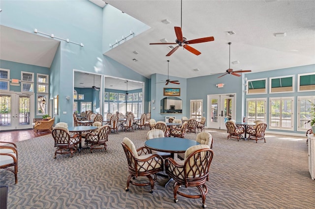 dining area with a wealth of natural light, french doors, a towering ceiling, and carpet flooring