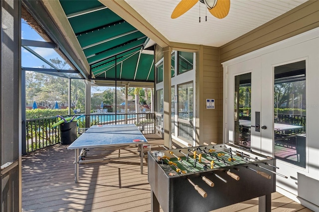 sunroom with a healthy amount of sunlight, a ceiling fan, and lofted ceiling