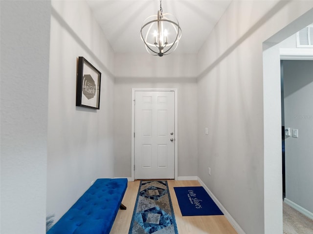 entryway featuring baseboards, wood finished floors, visible vents, and a chandelier