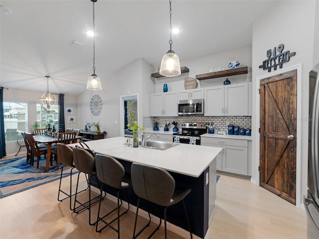 kitchen featuring a kitchen bar, appliances with stainless steel finishes, light countertops, and a sink