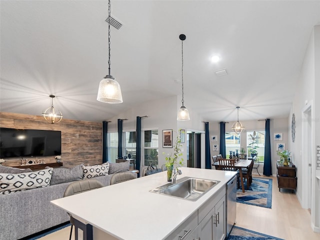 kitchen with wooden walls, visible vents, a sink, pendant lighting, and dishwasher