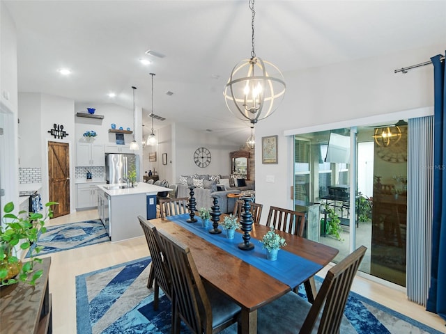 dining area featuring a notable chandelier, light wood-style flooring, visible vents, and lofted ceiling