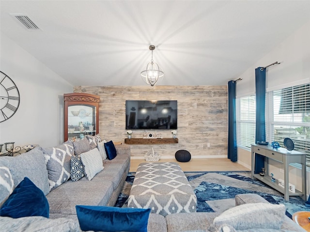 living area featuring visible vents, wood walls, an accent wall, and vaulted ceiling