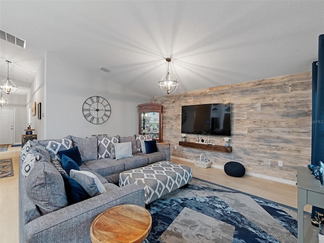 living room featuring wood finished floors, visible vents, lofted ceiling, and a chandelier