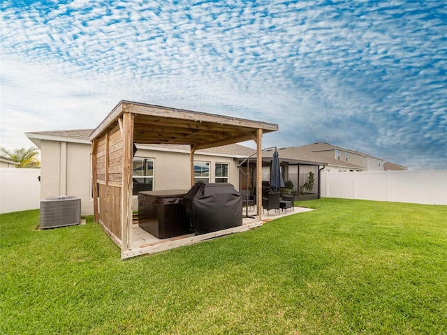 back of property with a hot tub, central air condition unit, stucco siding, a lawn, and a fenced backyard