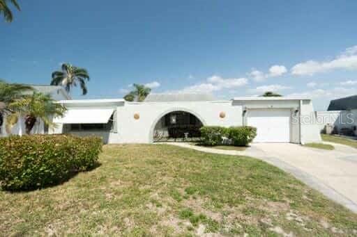 single story home featuring concrete driveway, an attached garage, a front lawn, and stucco siding