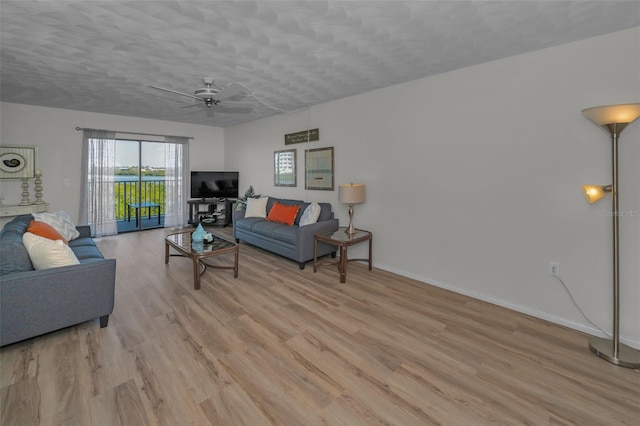 living room with a textured ceiling, baseboards, light wood-type flooring, and ceiling fan