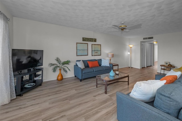 living area with visible vents, baseboards, ceiling fan, light wood-style floors, and a textured ceiling