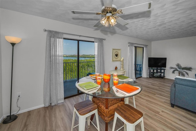 dining area featuring a ceiling fan, wood finished floors, baseboards, and a textured ceiling