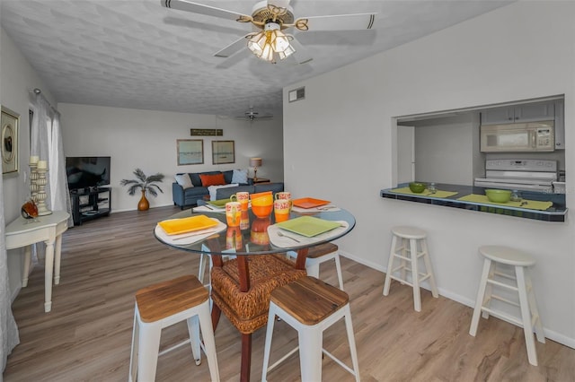 dining area featuring light wood-type flooring, baseboards, visible vents, and ceiling fan