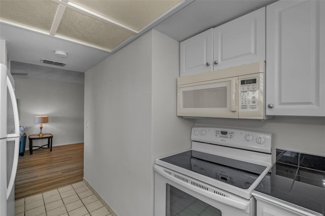 kitchen with visible vents, baseboards, light tile patterned floors, white cabinets, and white appliances