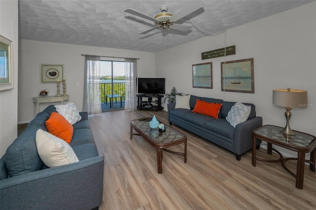 living room featuring light wood-style flooring, a textured ceiling, and a ceiling fan