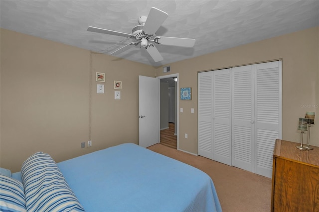 bedroom with a closet, a ceiling fan, visible vents, and carpet flooring