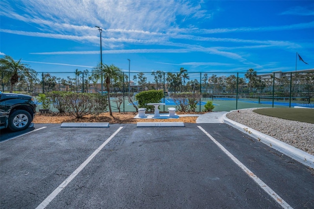 uncovered parking lot with a tennis court and fence