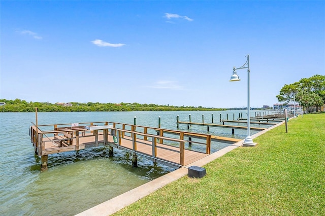 view of dock with a yard and a water view