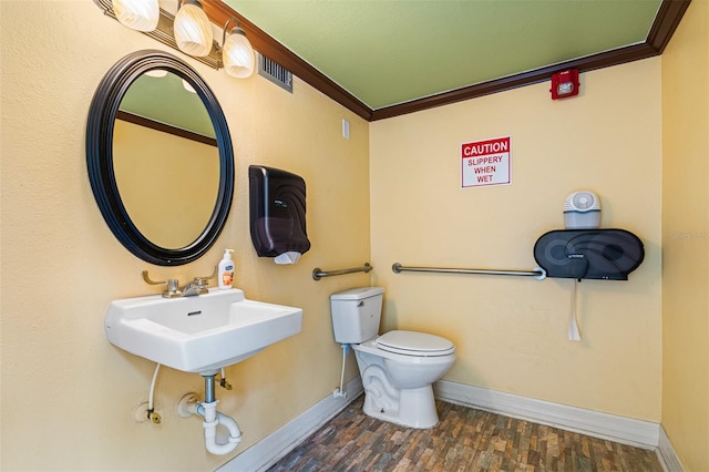 bathroom featuring baseboards, toilet, wood finished floors, and crown molding