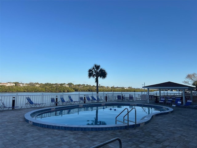 community pool featuring a gazebo, a patio area, a water view, and fence