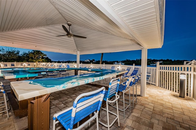 view of patio with ceiling fan, a community pool, outdoor dry bar, and fence