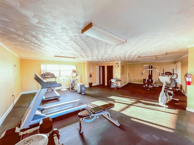 exercise area with baseboards, a textured ceiling, attic access, and ornamental molding