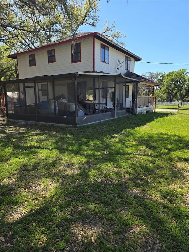 back of property with a lawn and a sunroom