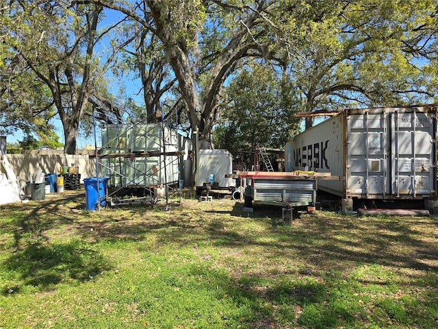 view of yard featuring an outdoor structure, fence, and an exterior structure