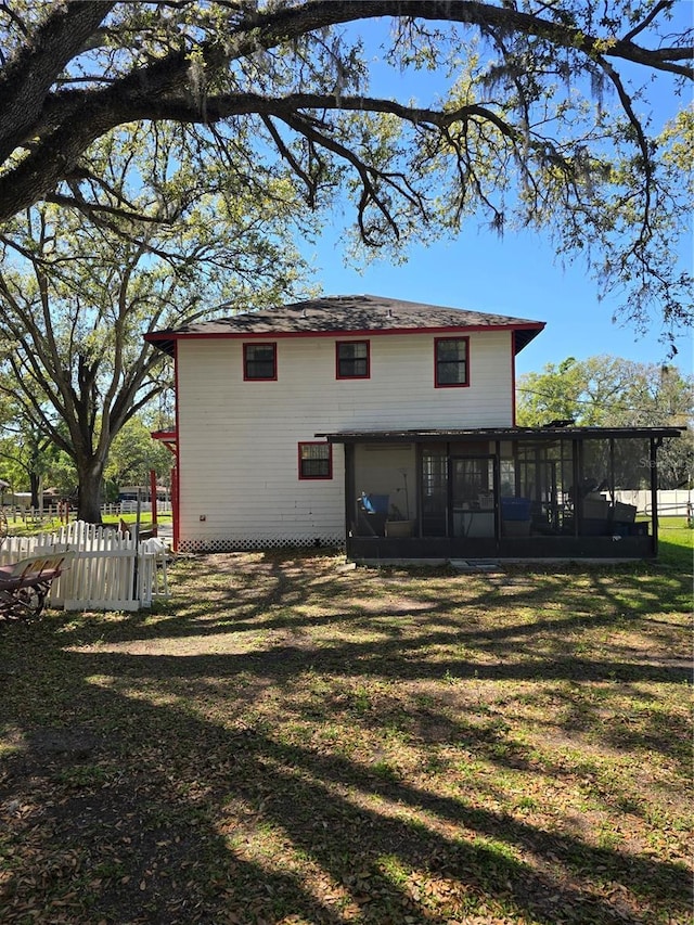 rear view of property with a yard, fence, and a sunroom