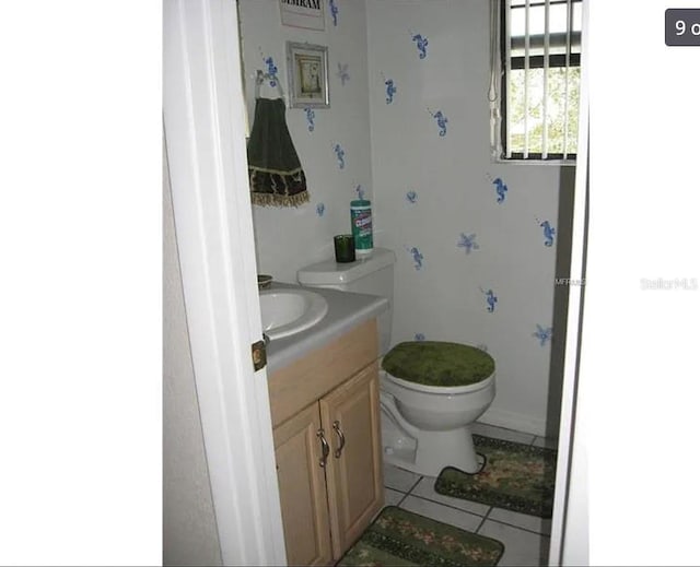 half bath with toilet, vanity, and tile patterned flooring