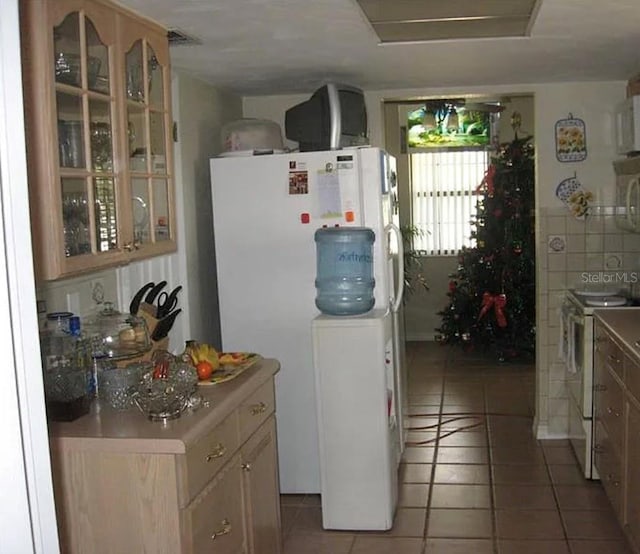 kitchen with light tile patterned floors, glass insert cabinets, white appliances, and light countertops