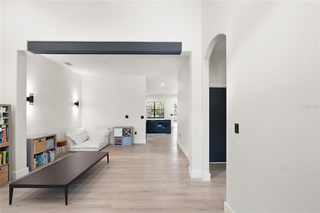 living area with visible vents, baseboards, arched walkways, and light wood finished floors