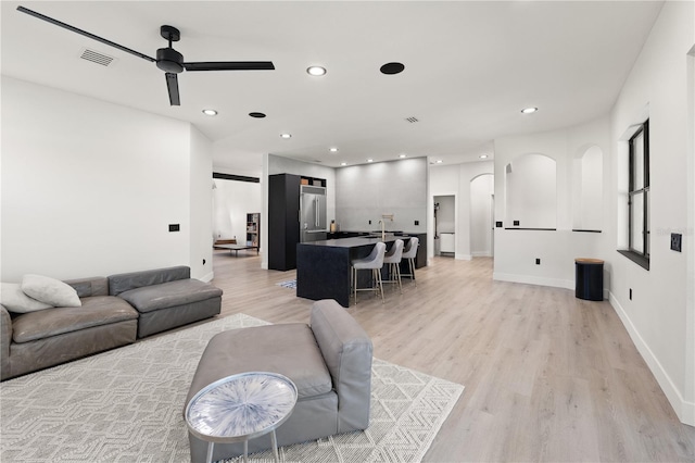 living room featuring visible vents, a ceiling fan, recessed lighting, arched walkways, and light wood finished floors