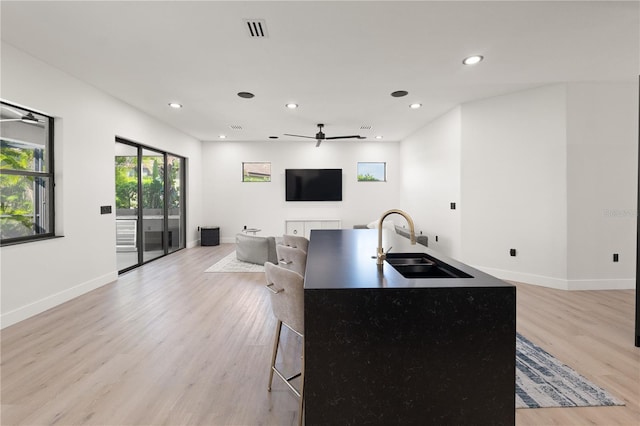 kitchen with visible vents, light wood-style flooring, a sink, open floor plan, and ceiling fan